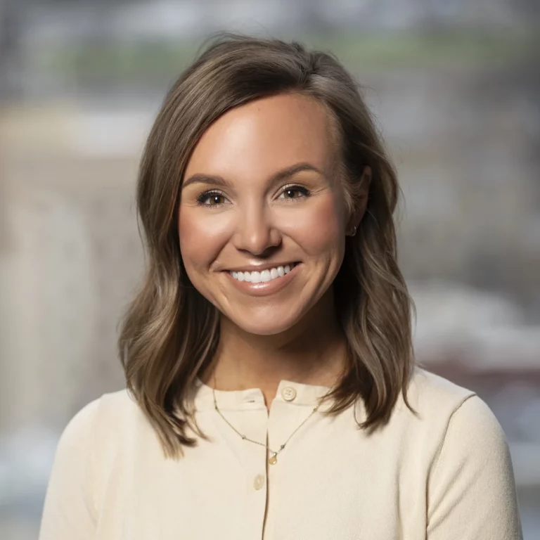 Kaley Tucker, a woman with shoulder-length brown hair wearing a cream-colored top, smiling at the camera.